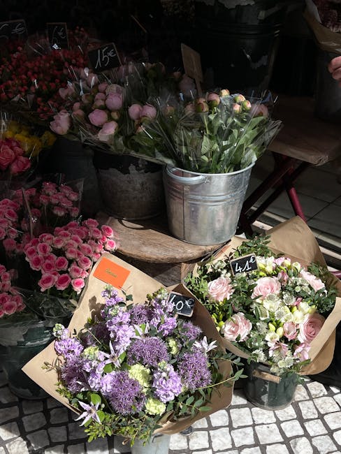 A woman standing in front of a floral shop on Kensington High Street W8, framed by a red canopy overhead, is selecting a bouquet from an array of fresh flowers. The display includes a variety of vibra