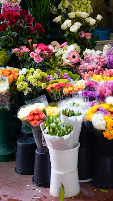 A vibrant floral display at Kentishtown Florist featuring a variety of fresh flowers arranged in black and white buckets. Prominent blooms include white roses, pink gerbera daisies, and multicolored t